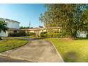 Cozy single-Gathering home featuring a well-manicured lawn and an inviting curved driveway with beautiful shrubbery at 631 Luzon Ave, Tampa, FL 33606