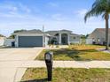 Charming single-story home with a well-manicured lawn, gray exterior, and two-car garage at 8702 Pinafore Dr, New Port Richey, FL 34653