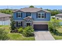 Charming two-story home with blue siding, stone accents, a dark garage door and landscaped yard at 13871 Carlow Park Dr, Riverview, FL 33579