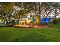 A beautiful landscaped backyard with lush green grass, garden beds, and a cozy seating area around the house at 1880 Belleair Rd, Clearwater, FL 33764