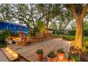 Serene backyard with a wooden deck, rocking chairs, mature trees and landscape lighting at 1880 Belleair Rd, Clearwater, FL 33764