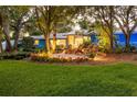Charming blue home featuring a cozy patio with seating, surrounded by lush greenery and mature trees at 1880 Belleair Rd, Clearwater, FL 33764