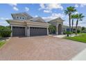 Inviting home featuring a three-car garage, large brick driveway, and manicured lawn at 32791 Natural Bridge Rd, Wesley Chapel, FL 33543