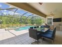 Screened pool area with large pool, attached hot tub, outdoor dining set, and stainless steel outdoor kitchen at 32791 Natural Bridge Rd, Wesley Chapel, FL 33543