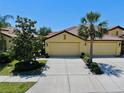 Two-car garage with well manicured yard featuring lush green grass and mature trees at 334 Mystic Falls Dr, Apollo Beach, FL 33572