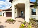 Inviting front porch with brick pavers and an arched entryway leading to the stylish blue front door at 5329 Windy Grove Dr, Wimauma, FL 33598