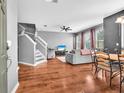 Open-concept living room with hardwood floors, staircase, comfortable seating, and bright natural light at 6851 Breezy Palm Dr, Riverview, FL 33578