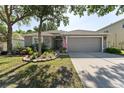 Charming single-story home with a gray exterior, lush landscaping, and an attached two-car garage at 5754 Sweet William Ter, Land O Lakes, FL 34639