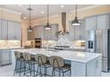 Elegant kitchen showcasing gray cabinets, stainless steel appliances, a large island with seating, and modern pendant lighting at 11423 Shoreline Trl, Parrish, FL 34219