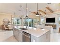 Open-concept kitchen with a large island, pendant lighting, and stainless steel appliances adjacent to the dining and living areas at 11423 Shoreline Trl, Parrish, FL 34219