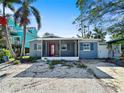 Charming single story home featuring a covered porch with a red front door and gravel landscaping at 1214 Bay Shore Blvd, Indian Rocks Beach, FL 33785