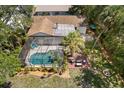 Aerial view of a backyard featuring a screened pool, deck, outdoor seating, and lush landscaping at 1628 12Th Sw St, Largo, FL 33778