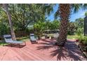 Relaxing backyard deck area with outdoor seating, mature trees, and inviting landscaping at 1628 12Th Sw St, Largo, FL 33778