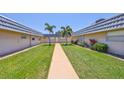 Exterior view of a well-kept community featuring landscaped grounds, a grassy courtyard, and palm trees at 1802 Bedford Ter # 187, Sun City Center, FL 33573