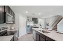 Open-concept kitchen boasts stainless steel appliances, dark cabinetry, island, and staircase access at 3332 Ivy Hollow Dr, Plant City, FL 33565