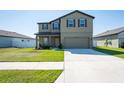 Two-story home featuring a well-kept lawn, two-car garage, and neutral-toned exterior at 35853 Buttonweed Trl, Zephyrhills, FL 33541