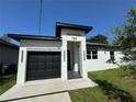Modern home exterior with a black garage door, a contemporary entrance and meticulous landscaping at 7208 N Glen Ave, Tampa, FL 33614