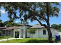 Contemporary single-Gathering home with manicured lawn and mature shade tree in the front yard at 7208 N Glen Ave, Tampa, FL 33614