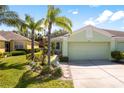 Home exterior with attached two car garage, well-maintained lawn and garden featuring decorative plants at 11466 Captiva Kay Dr, Riverview, FL 33569
