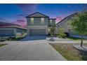 Two-story home with a two-car garage, landscaped front yard, and colorful sunset sky at 15718 Fort Island Pl, Sun City Center, FL 33573