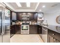 Modern kitchen with stainless steel appliances, dark cabinetry, and tile backsplash at 19418 Gulf Blvd # 507, Indian Shores, FL 33785