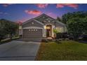 Charming single-story home with a well-manicured lawn and attached two-car garage at twilight at 19610 Sunset Bay Dr, Land O Lakes, FL 34638