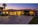 Inviting single-Gathering home exterior at twilight, featuring a large driveway, well-kept landscaping and attached screened in garage at 3235 Seaway Dr, New Port Richey, FL 34652