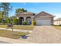 Inviting home featuring a paved driveway, lush lawn, and an attached two-car garage with a beautiful blue sky backdrop at 9127 Irondale Ln, Hudson, FL 34667