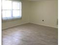 Bright bedroom features tile floors, neutral walls, and a large window with blinds at 10817 Fillmore Ave, Port Richey, FL 34668