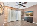 Bright living room with tile flooring, a ceiling fan, modern TV, wood accent wall and sheer curtains at 1180 39Th N St, St Petersburg, FL 33713