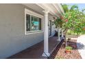 Close-up of the inviting front porch with brick flooring, decorative columns, and a flowering tree at 1183 35Th Ne Ave, St Petersburg, FL 33704