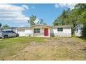 Inviting single-story home with a red door, complemented by a lush green front lawn at 12701 Cornell Ct, Hudson, FL 34667