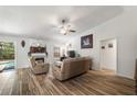 Cozy living room featuring wood-look tile, a ceiling fan, and a fireplace at 12815 Tallowood Dr, Riverview, FL 33579
