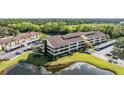 Aerial view showcases the condo building, adjacent parking, and a tranquil pond surrounded by trees at 13610 S Village Dr # 4212, Tampa, FL 33618