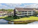 Scenic view of condo building with serene pond, lush lawn, and mature landscaping at 13610 S Village Dr # 4212, Tampa, FL 33618