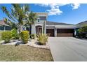 Gray two-story home featuring a three-car garage, well-kept lawn and attractive desert-style landscaping at 13622 Tonya Anne Dr, Riverview, FL 33579