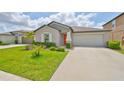 Charming single-story home featuring a well-manicured lawn, tasteful landscaping and an inviting orange front door at 16665 Delia St, Wimauma, FL 33598