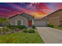 Charming single-story home featuring a well-manicured lawn, tasteful landscaping and an inviting orange front door at 16665 Delia St, Wimauma, FL 33598