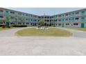 Lovely condo building with well-kept landscaping, circular driveway, and blue balcony railings at 1950 59Th N Ave # 208, St Petersburg, FL 33714