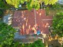 Overhead view of a well-maintained, reddish-brown roof with surrounding mature trees at 3212 E Henry Ave, Tampa, FL 33610