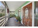 Charming covered front porch with seating area, wooden floors, and a wooden front door at 8614 Hibiscus Dr, Tampa, FL 33637