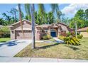 Beautiful home featuring a well-manicured lawn, mature landscaping, and an attached two-car garage at 1135 Wyndham Lakes Dr, Odessa, FL 33556