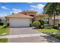 Beautiful single-story home with a tile roof, manicured lawn, and a brick paved driveway at 16055 Golden Lakes Dr, Wimauma, FL 33598