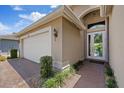 Inviting front entrance with a glass front door, brick walkway, and a two-car garage at 16055 Golden Lakes Dr, Wimauma, FL 33598
