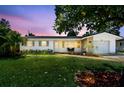 Exterior view of a well-maintained home with lush lawn and tropical landscaping during a beautiful dusk at 1751 Ashton Abbey Rd, Clearwater, FL 33755