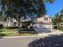 Lovely two-story home with three-car garage, mature trees, manicured lawn, and a concrete driveway in a neighborhood setting at 19116 Nature Palm Ln, Tampa, FL 33647