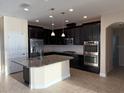 Modern kitchen featuring dark cabinetry, stainless steel appliances, and a granite-topped island at 19514 Sea Myrtle Way, Tampa, FL 33647