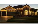 Beautiful stone home illuminated with warm string lights and a brick driveway at night at 28857 Picana Ln, Wesley Chapel, FL 33543