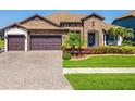 Charming home featuring a stone facade, well-manicured lawn, and a three-car garage at 28857 Picana Ln, Wesley Chapel, FL 33543