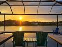 Breathtaking sunset view from the screened lanai with pool overlooking the tranquil lake, creating a serene backyard oasis at 28857 Picana Ln, Wesley Chapel, FL 33543
